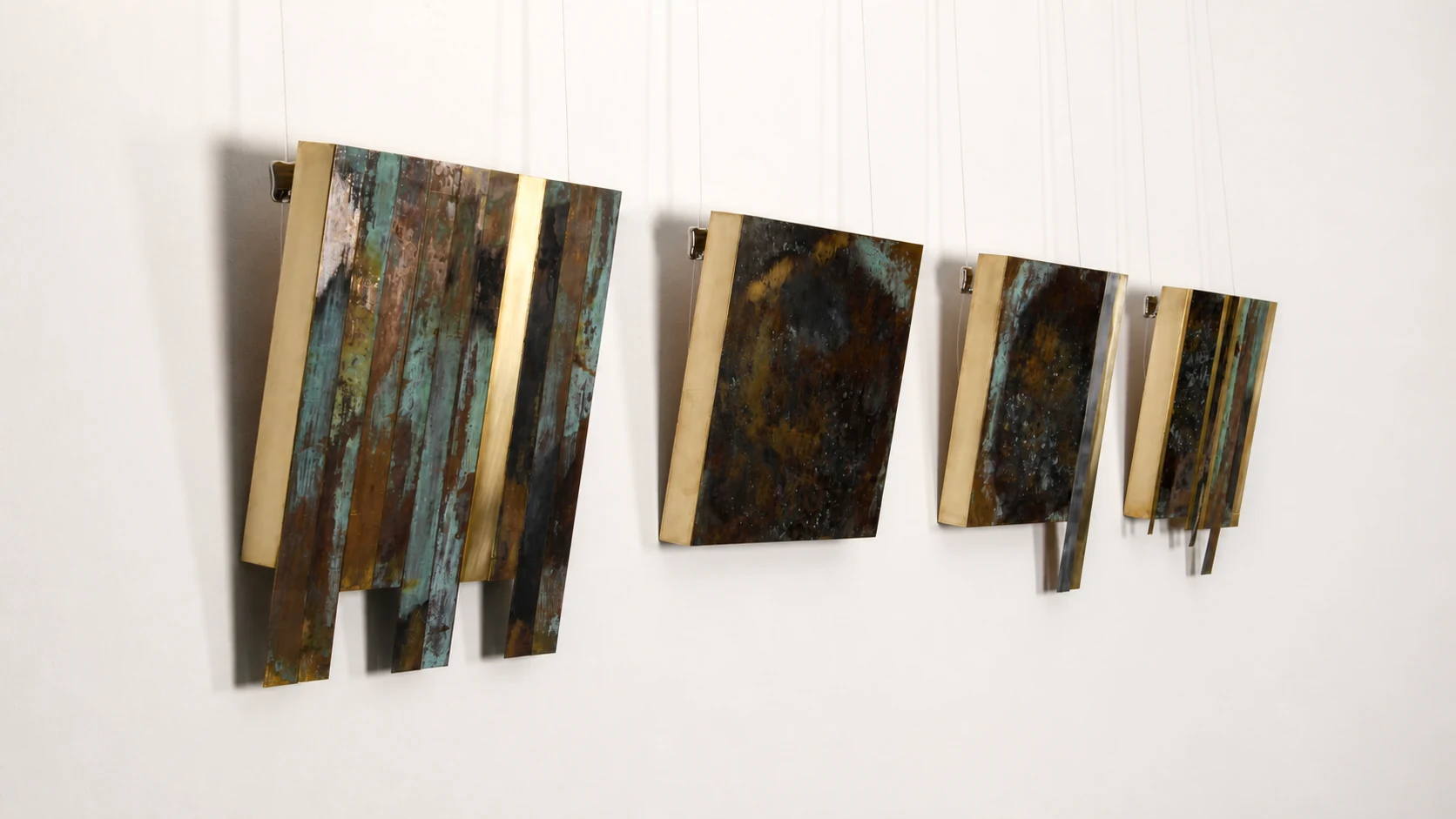 Instalación de cuatro piezas de metal patinado en una pared de galería